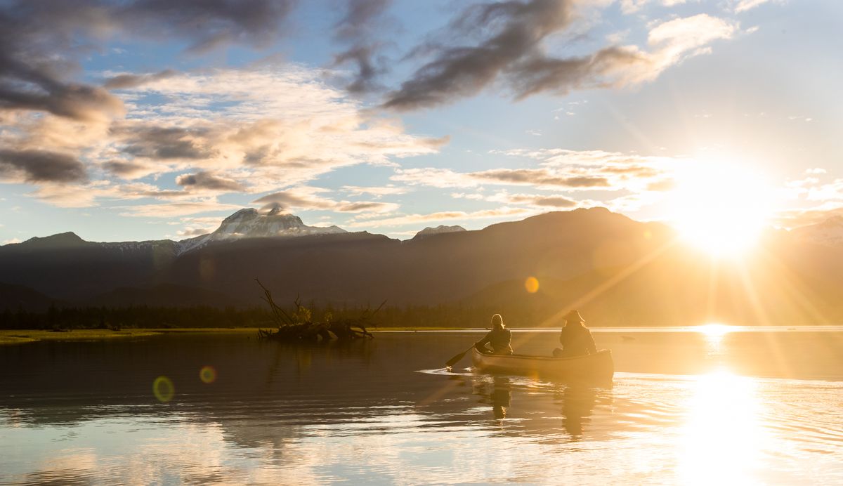 Canoeists paddling into a golden sunset on a Sea to Sky lake
